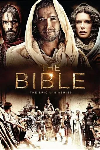 The poster features a dramatic, sepia-toned scene with three central figures—two men in hooded robes and a woman with a contemplative expression—against a backdrop of ancient figures in a dusty, historical setting. The warm, golden lighting evokes a sense of mystery and epic storytelling, while t...