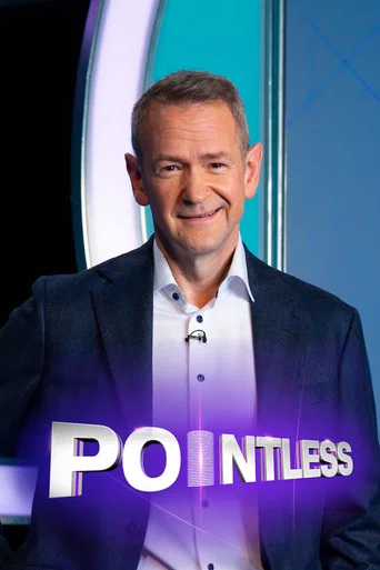 Two men stand behind a desk, one in a dark suit and the other in a blue jacket, both smiling at the camera. The background features vibrant purple and pink hues with the show's title prominently displayed.