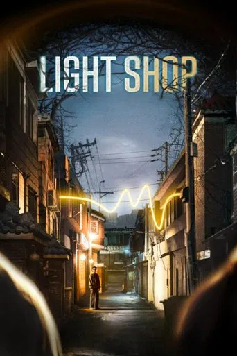 The poster features a dimly lit, narrow alleyway at dusk, evoking a mysterious and atmospheric mood. Warm yellow lights from streetlamps and decorative hanging lights create a cozy yet eerie ambiance. Silhouettes of people stand in the distance, adding depth and mystery to the scene. The title "L...