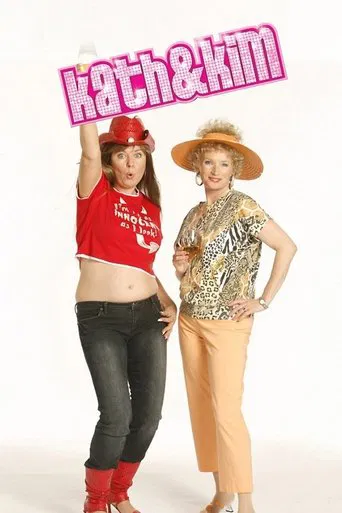 Two stylish women pose against a white background, exuding confidence with their vibrant outfits. The woman on the left wears a red top and hat, while the woman on the right dons a patterned blouse and straw hat. Their playful expressions and dynamic poses suggest a fun, energetic TV show.
