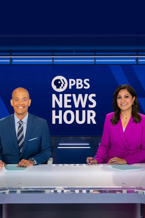 Two news anchors stand confidently in a vibrant studio, with one in a blue suit and the other in a striking purple ensemble. The backdrop features bold blue and white tones, emphasizing the show's professional yet energetic atmosphere.