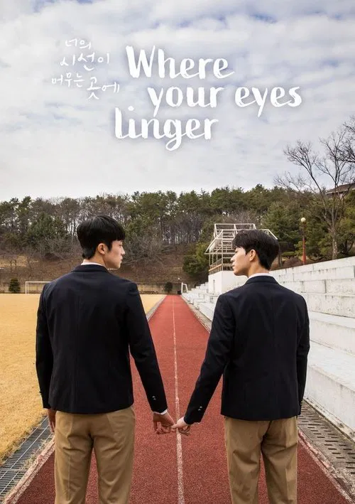 Two men in dark jackets and khaki pants walk hand-in-hand along a red path, their expressions serious and contemplative. The scene is set against a backdrop of trees and a cloudy sky, evoking a sense of longing and introspection.