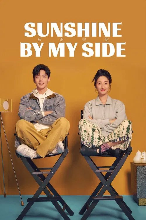 The poster features two individuals seated on folding chairs against a warm, mustard-yellow background. The man on the left wears a gray sweater and tan pants, while the woman on the right dons a light-colored blouse and patterned skirt. Their expressions are relaxed and friendly, suggesting a ca...