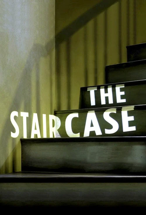 The poster features a dramatic staircase with bold, illuminated text reading "THE STAIRCASE." The warm, golden lighting creates an eerie atmosphere, while the shadowy figure in the background adds mystery.
