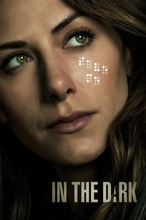 The poster features a close-up of a woman with green eyes, her expression intense and mysterious. The background is dark, emphasizing the subtle glow of white light on her face. The title "In the D:RK" is prominently displayed at the bottom in bold, metallic letters. The overall mood is suspensef...