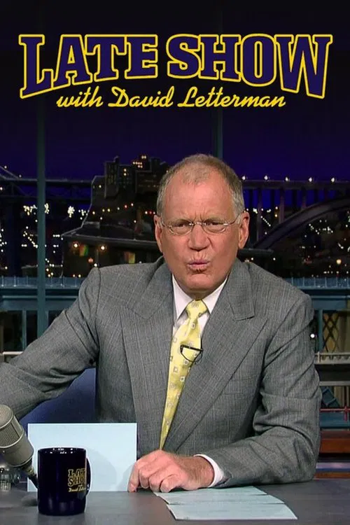 A man in a gray suit sits at a desk with a mug, looking directly at the camera against a cityscape backdrop. The poster features bold yellow text and a warm, inviting mood.