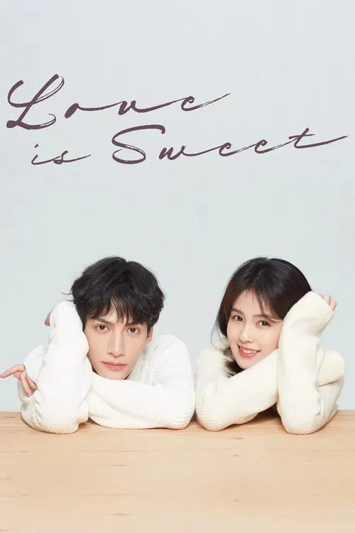 A couple in white sweaters lies on a wooden floor, exuding a romantic and intimate mood. The soft pink and white color scheme, combined with the elegant script text "Love is Sweet," creates a visually appealing and emotionally resonant image.
