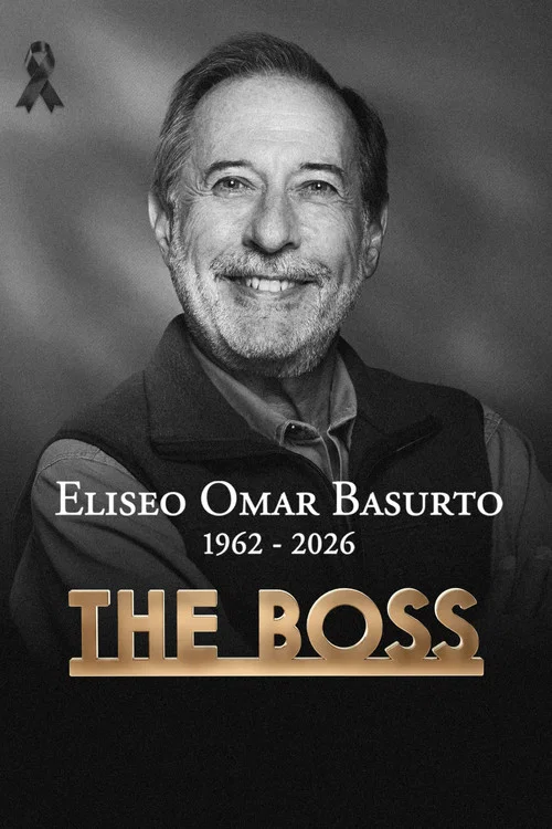 A middle-aged man with a mustache stands behind a wooden desk, holding a stack of office cubicles. The scene is warmly lit with a cozy, professional atmosphere. The poster features bold, golden text at the bottom reading "THE BOSS," suggesting a corporate or leadership-themed show.