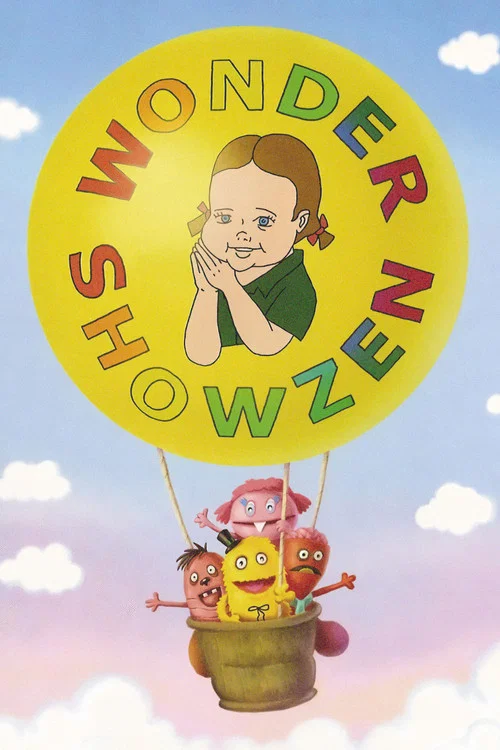 This vibrant poster features a cheerful yellow balloon with "WONDER SHOWZEN" written in colorful letters, accompanied by a smiling girl peeking through the rim. Three children joyfully ride in a basket, exuding happiness and wonder against a bright blue sky with fluffy white clouds. The overall m...