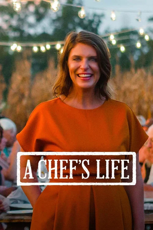 A woman in a warm orange dress stands proudly at an outdoor gathering, surrounded by friends and family. The festive atmosphere is enhanced by string lights and rustic decor. The mood is joyful and celebratory, capturing the essence of a lively social event.